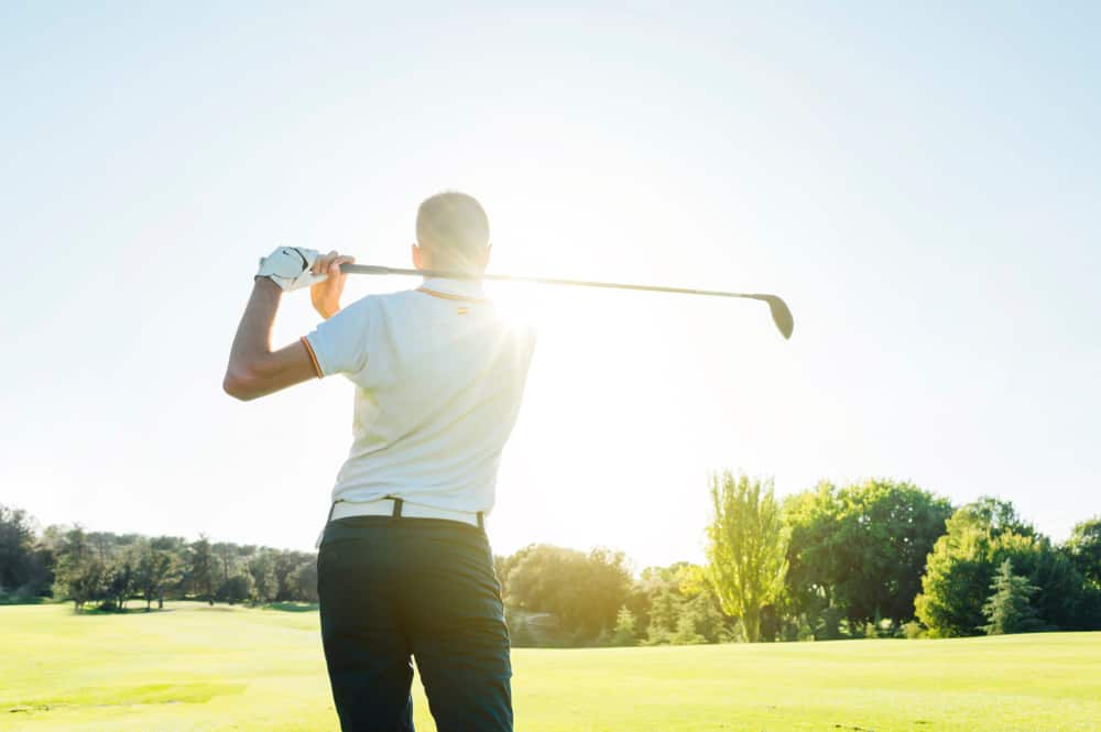 Male golf player teeing off golf ball from tee