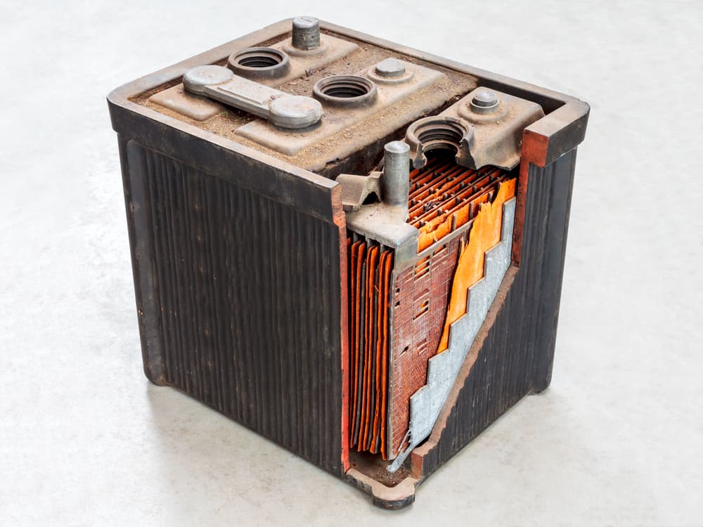 Old car battery with partly opened body on a light grey background