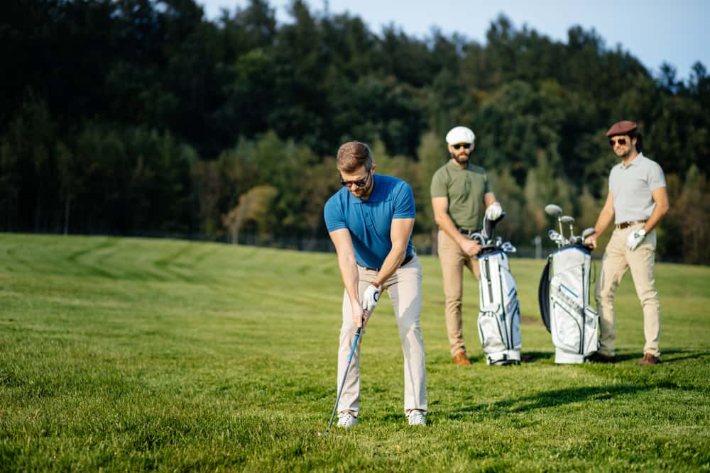 Stylish multicultural friends spending time together while playing golf on golf course