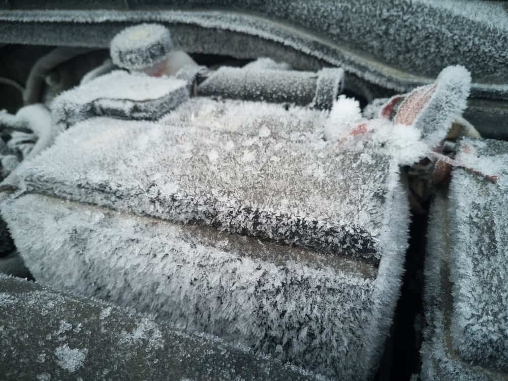 The engine compartment is covered with snow and ice after a long parking