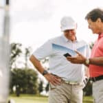 Two golf player standing together using mobile phone
