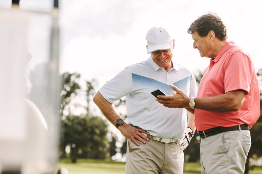 Two golf player standing together using mobile phone