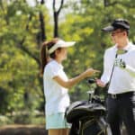 Young businessman and caddy playing golf in the lawn in the city center