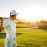 Young man holding a golf club and looking away on a sunny day.