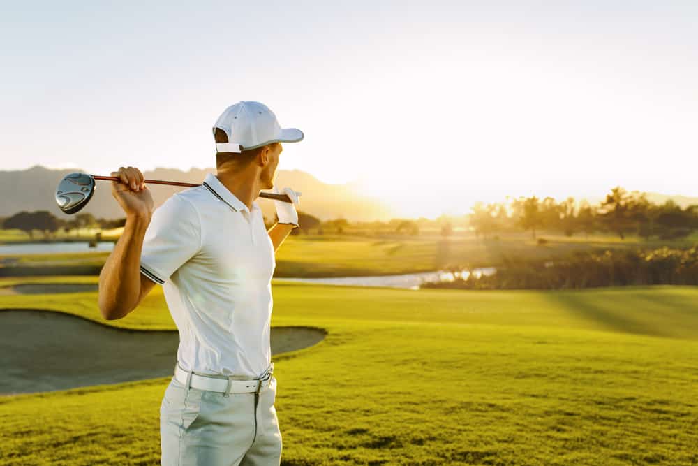 Young man holding a golf club and looking away on a sunny day.