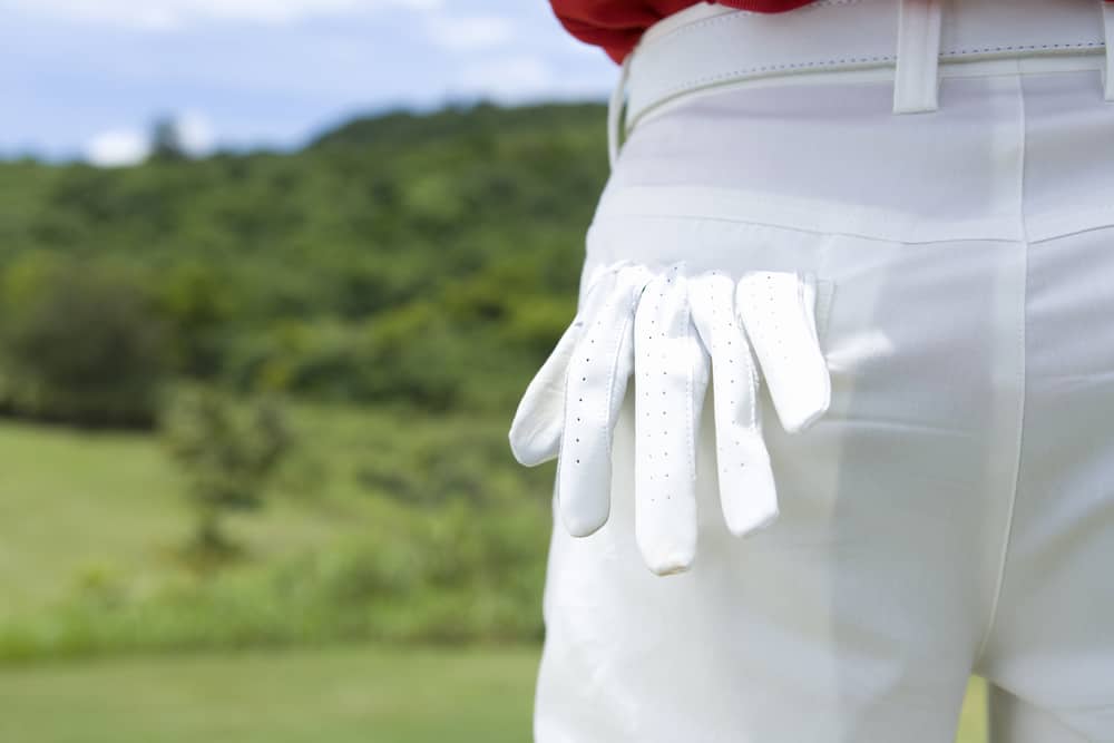 golfer putting gloves into pocket