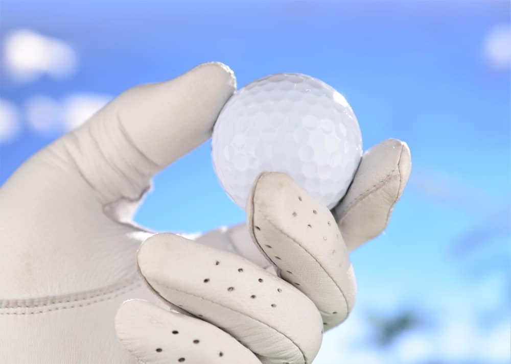 hand in glove holding golf ball