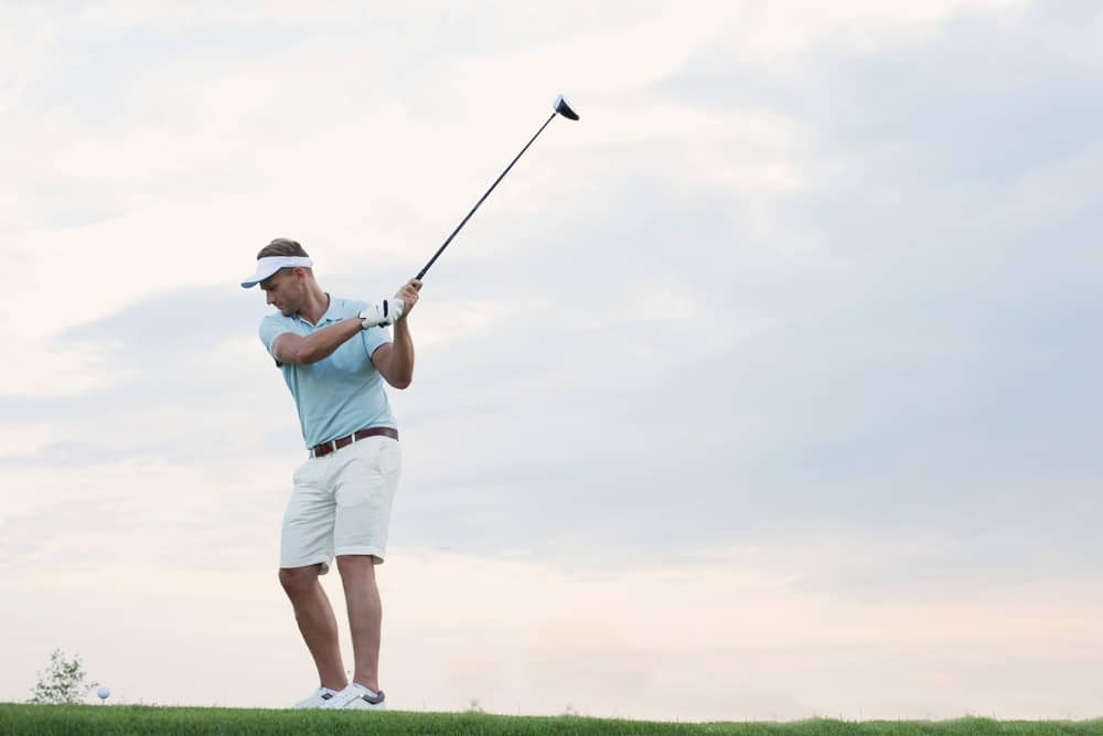 left handed man playing golf against sky