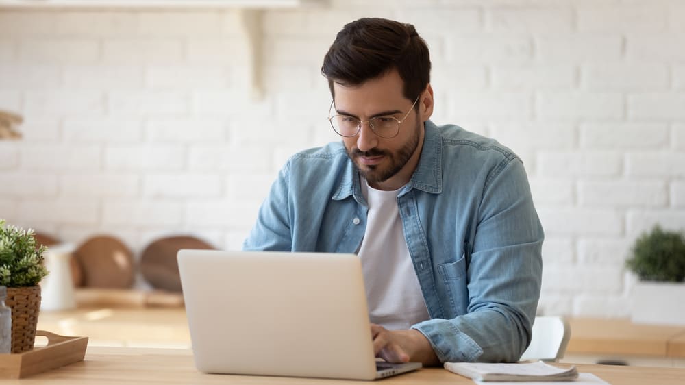 man wearing glasses working on laptop online