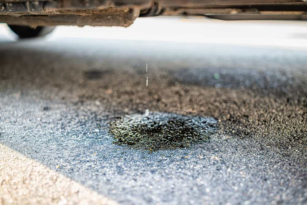 vehicle leaking fuel with puddle causing damage to asphalt