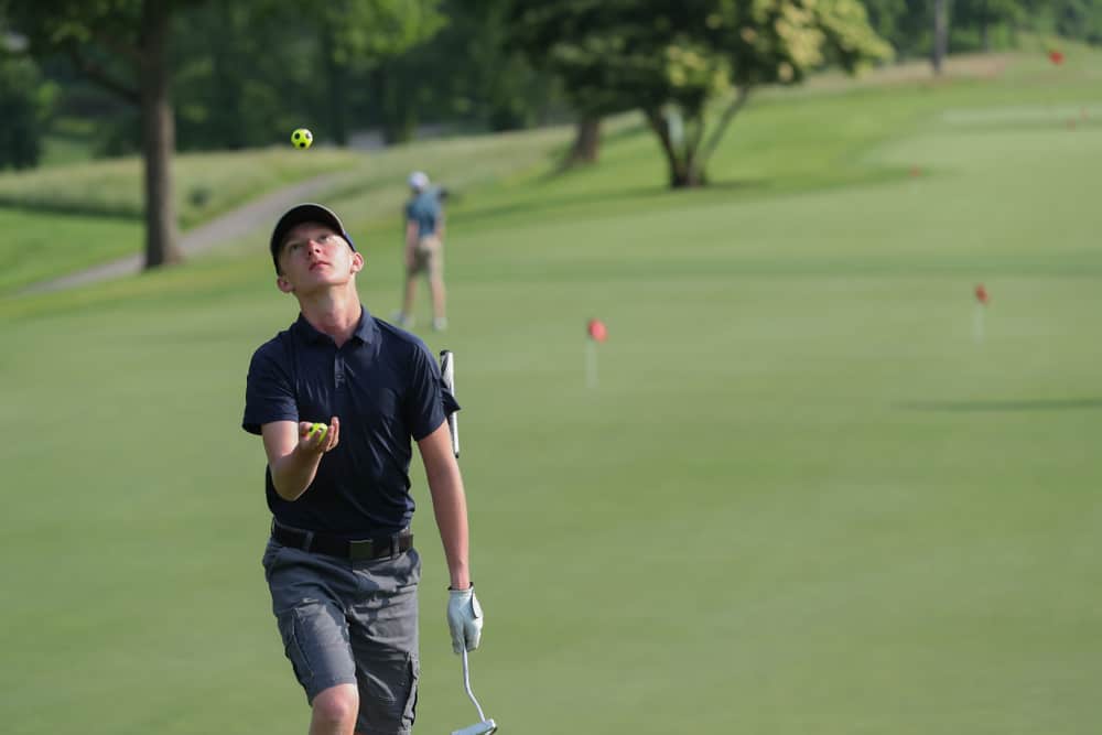 A junior golfer juggles golf balls