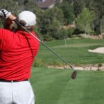 Male golfer with red shirt successfully hitting ball on green