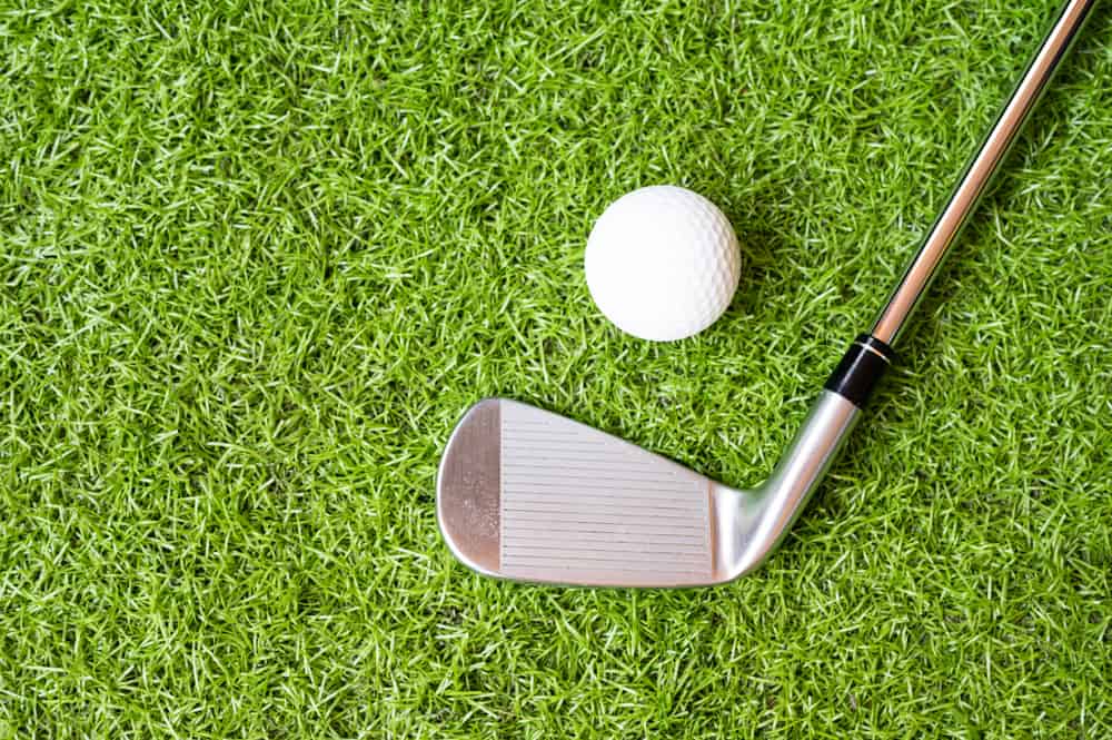 Top view golf club and golf ball on green grass background