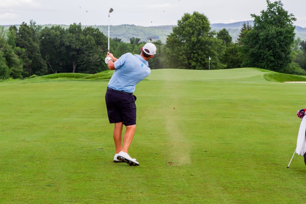 A golf hits an approach shot from the fairway in to the green