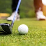 Golf ball on green grass ready to be struck at golf club