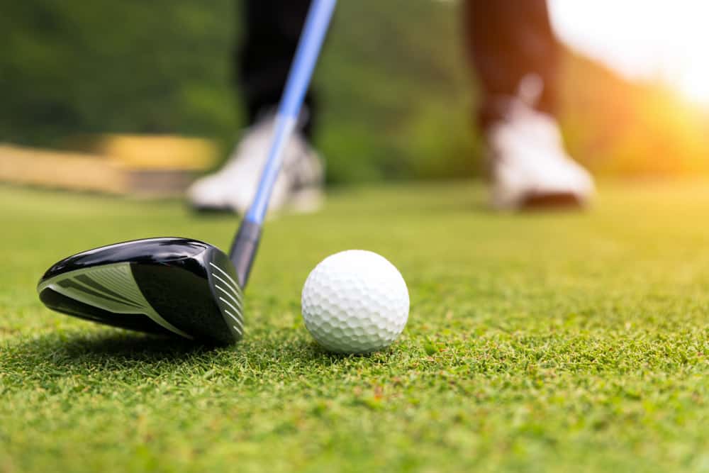 Golf ball on green grass ready to be struck at golf club