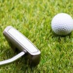 Golf ball with putter on green course