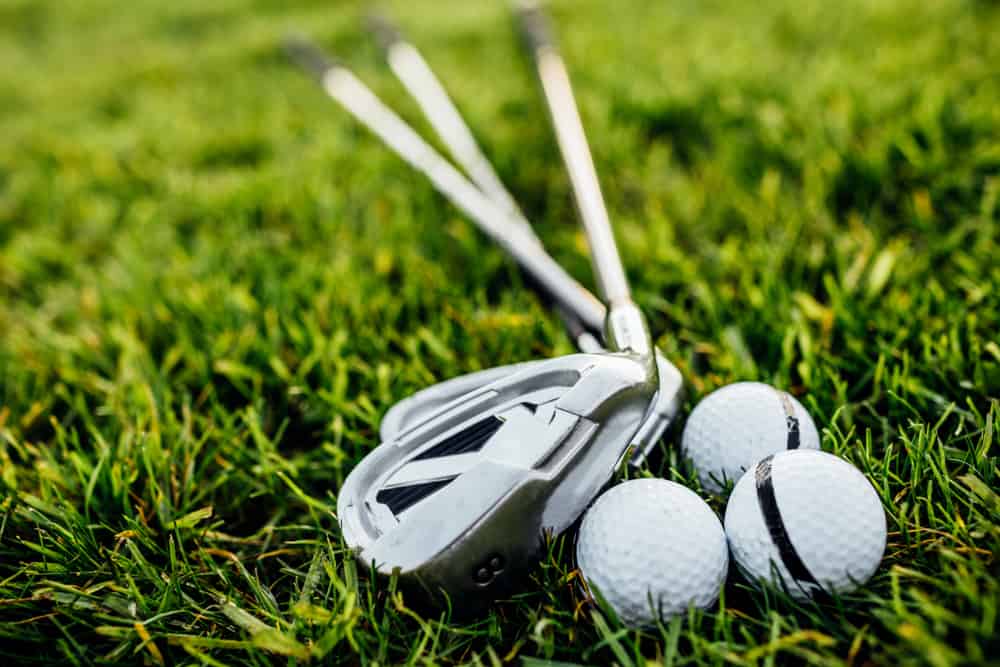 Golf balls and golf club on green grass