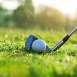 Golf clubs and golf balls on a green lawn