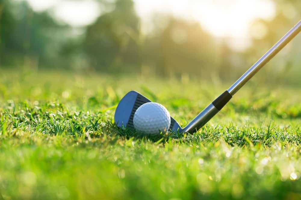 Golf clubs and golf balls on a green lawn