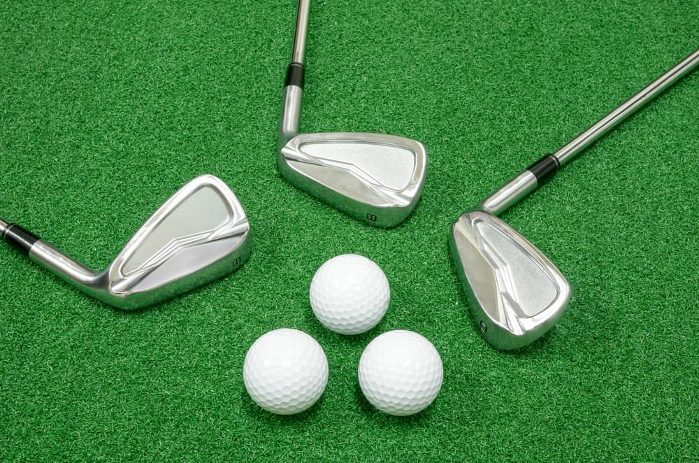 Golf clubs and golf balls placed on artificial grass