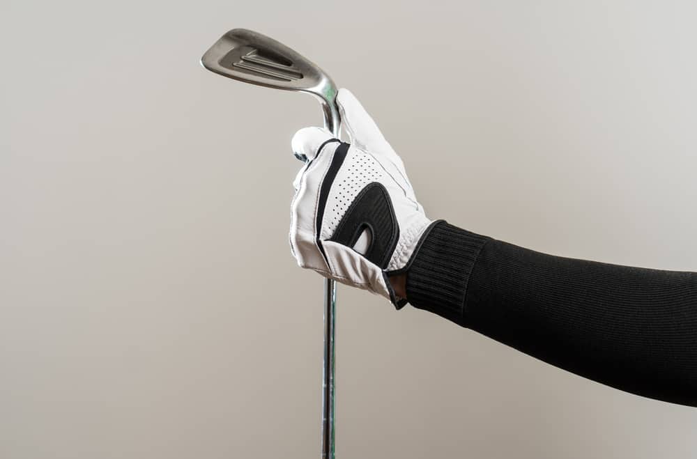 Golfer Wearing Golf Glove holding iron wage, golf equipment