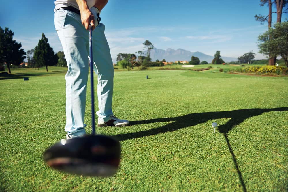 Golfer hitting driver club on course