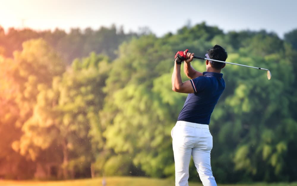 Golfer hitting golf shot with club on course