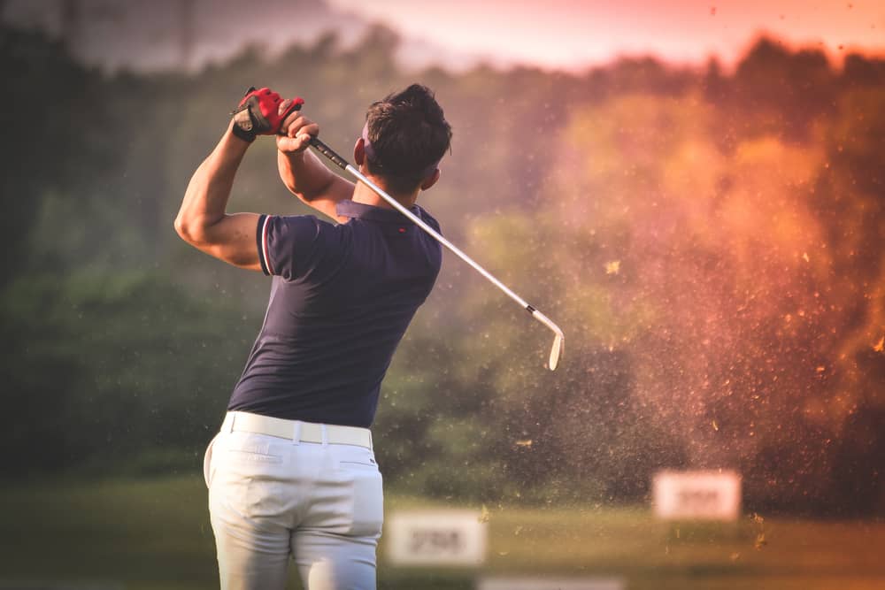 Golfer hitting golf shot with club