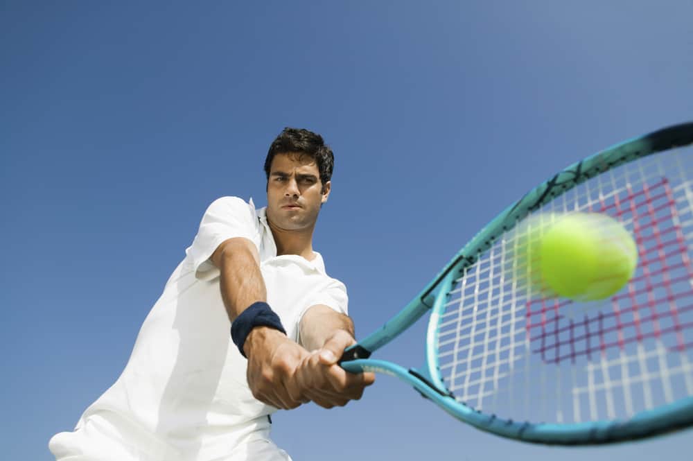 Low angle view of determined young man playing tennis