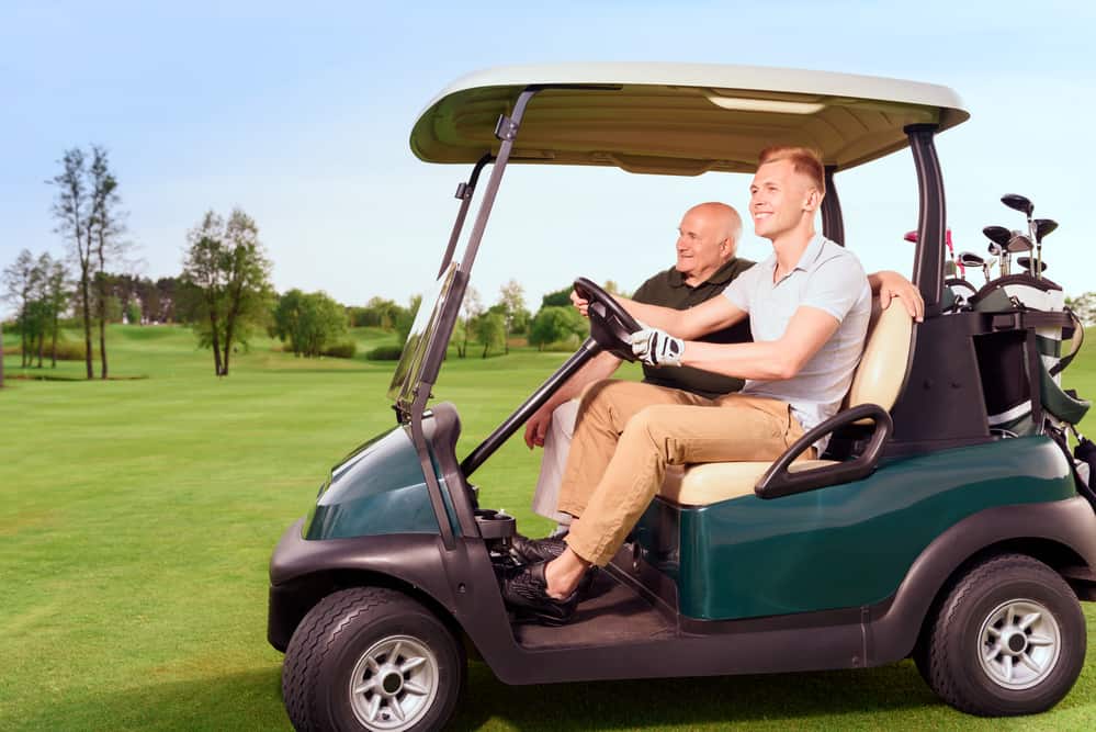 Side view of two golfer driving cart