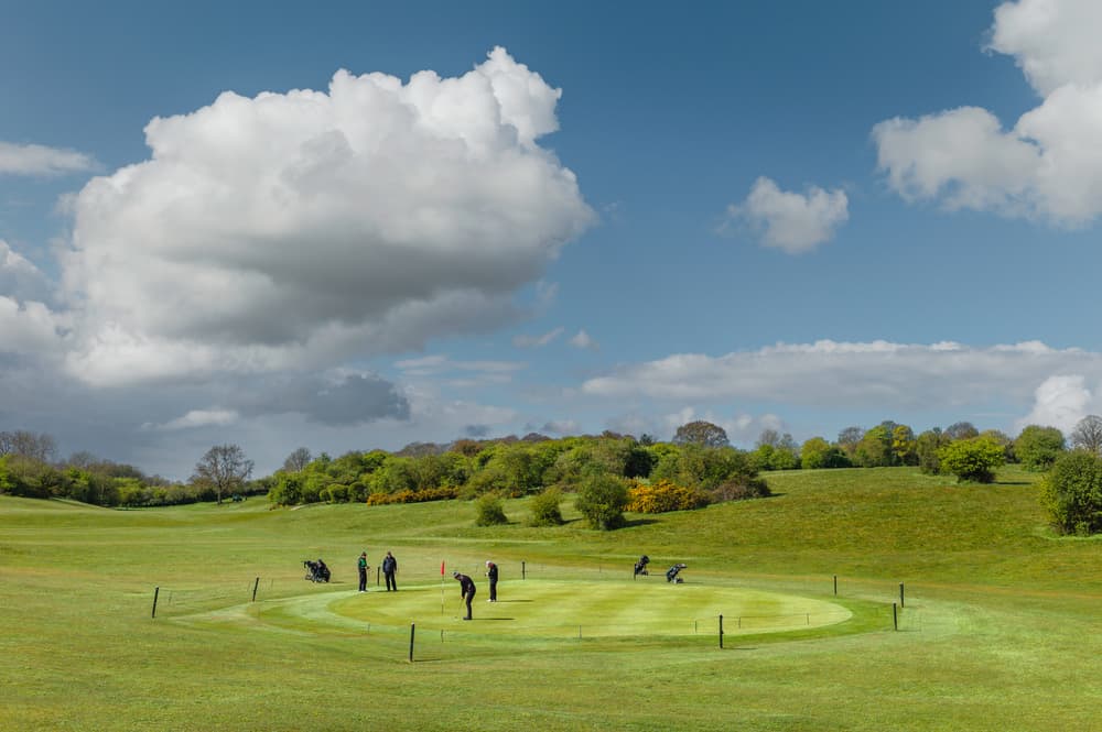 View across public parkland and golf course with golfers on bright morning