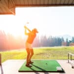 Young woman practices her golf swing on driving range