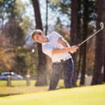 golfer playing a chip shot on a golf course on a bright sunny day