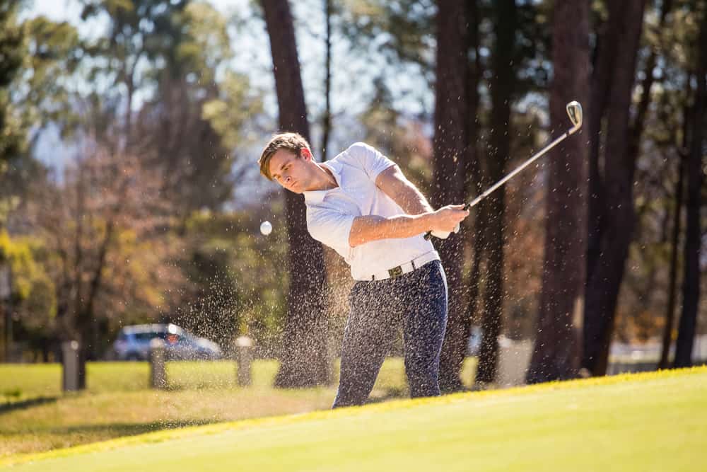 golfer playing a chip shot on a golf course on a bright sunny day