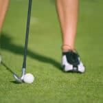 lady golfer prepares for iron shot at golf driving practice range