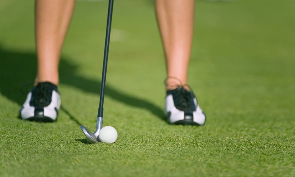 lady golfer prepares for iron shot at golf driving practice range