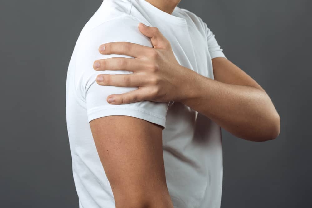 man on gray background holding his shoulder