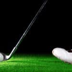 man ready to hit golf ball with golf iron on black background