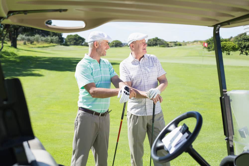 Golfing friends beside buggy