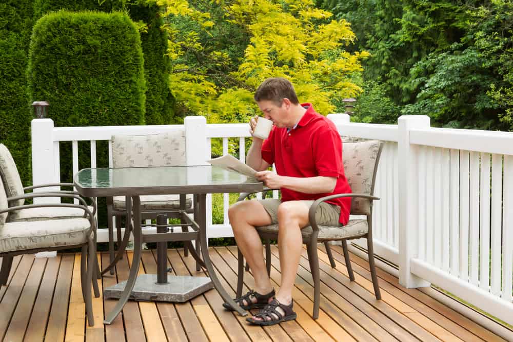 Mature Man Enoying Morning Coffee on Outdoor Patio reading magazine