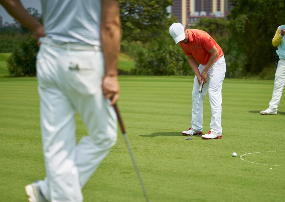 Asian man putting on green in golf course