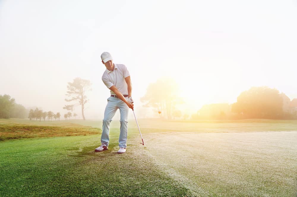 Golfer chipping onto the green at sunrise