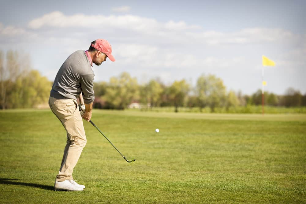 Male golf player pitching ball onto green