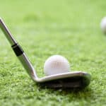 Selective golf club and golf ball on green grass background