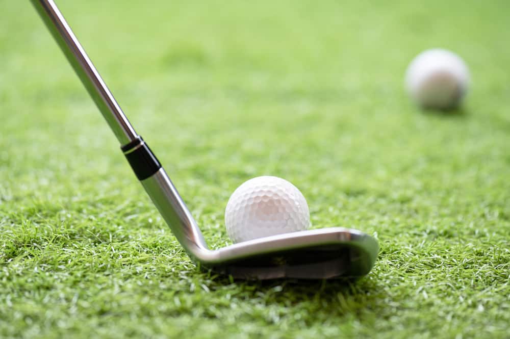 Selective golf club and golf ball on green grass background