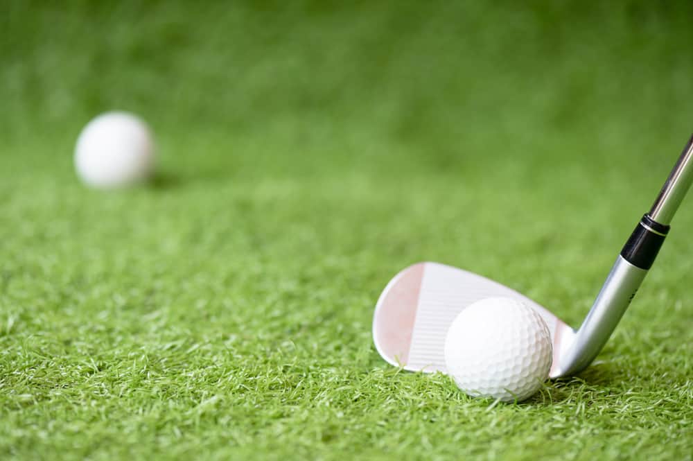 Selective golf club and golf ball on green grass background