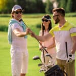 Two men and a woman are choosing golf clubs