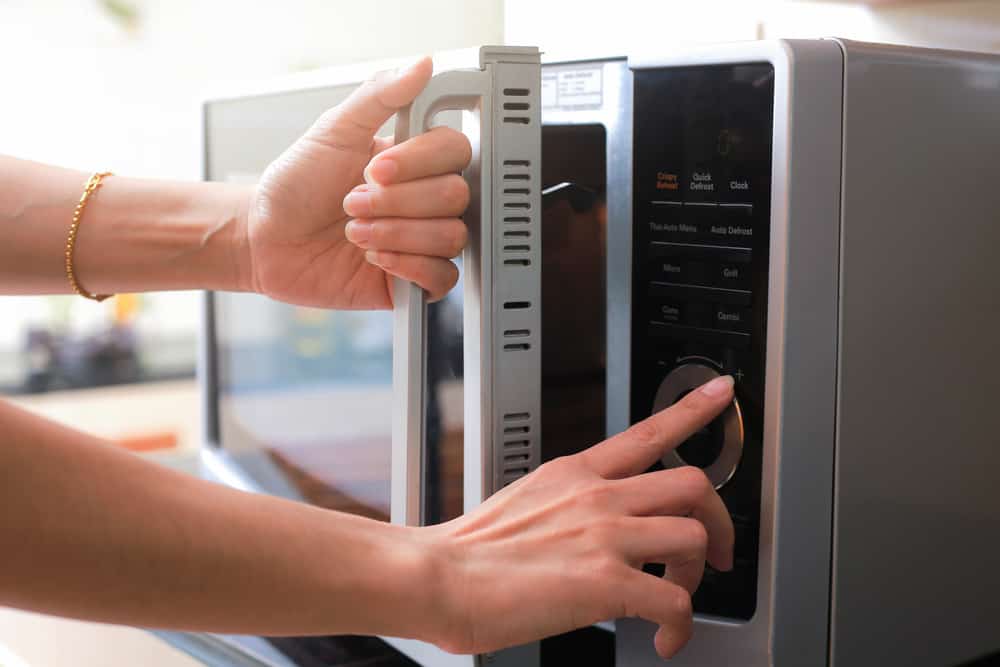 Woman's Hands Closing Microwave Oven Door