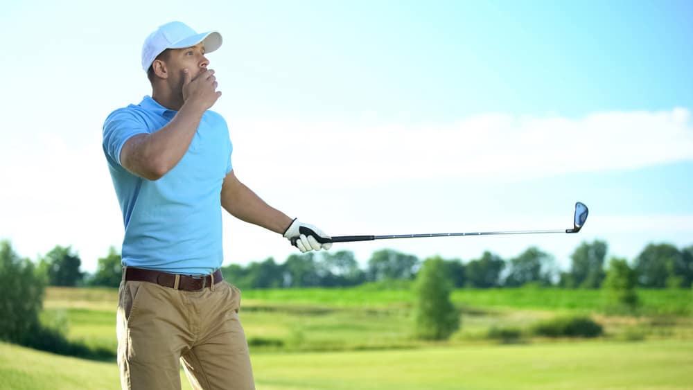 male golf player hitting ball, surprised with unsuccessful shot